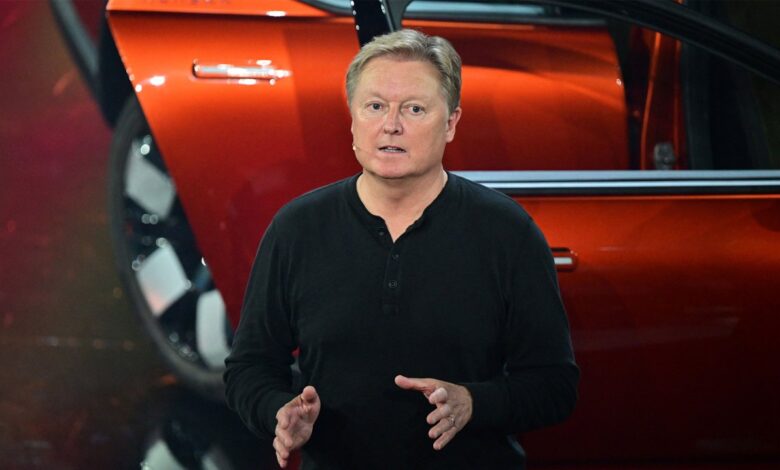 CEO speaking at a product launch event, standing in front of a vibrant red car.