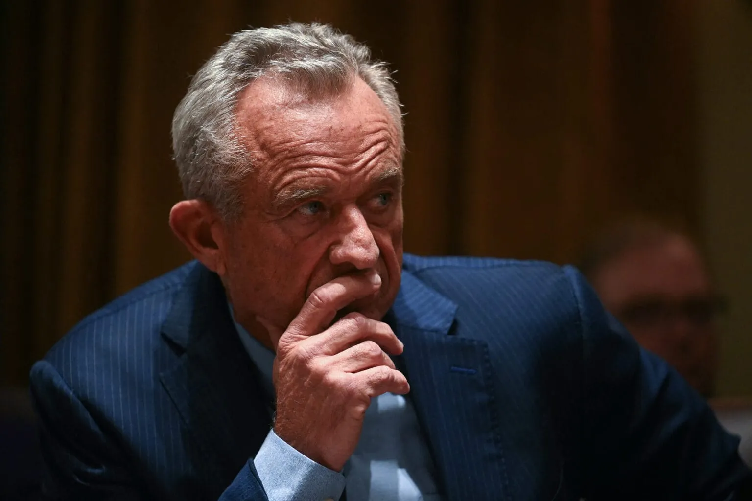 Robert F. Kennedy Jr. during a Senate hearing, appearing thoughtful with hand to chin.
