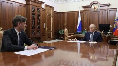 Vladimir Putin, President of Russia, sits across a large table from Dmitry Bakanov, head of Roscosmos, in a formal meeting.