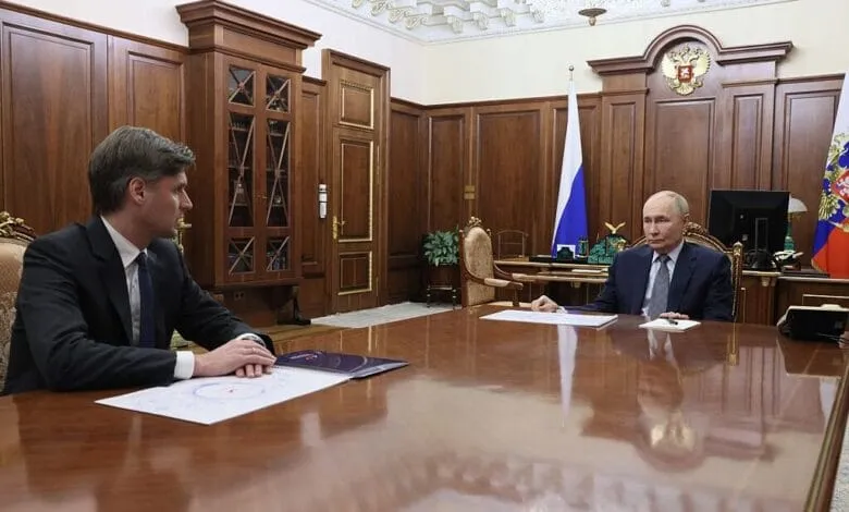 Vladimir Putin, President of Russia, sits across a large table from Dmitry Bakanov, head of Roscosmos, in a formal meeting.