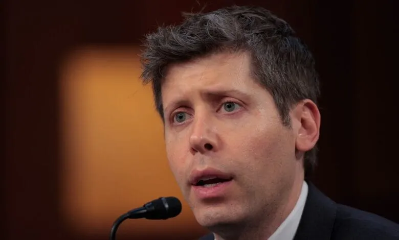 Close-up of Sam Altman speaking into a microphone, his expression is serious.