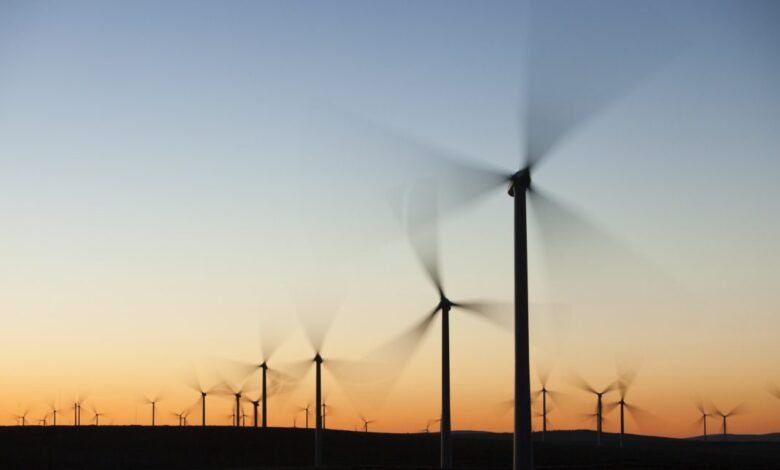 Wind turbines spinning at sunset, creating motion blur. Clean energy, renewable power.