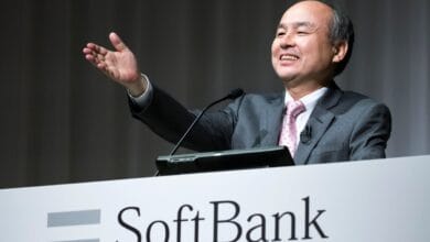 Masayoshi Son, CEO of SoftBank Group, smiles and gestures while speaking at a podium.