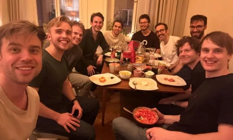 A group of smiling men enjoy a meal together at a table indoors.