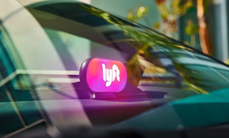 Close-up of a Lyft illuminated sign on a car's dashboard, glowing pink and purple.