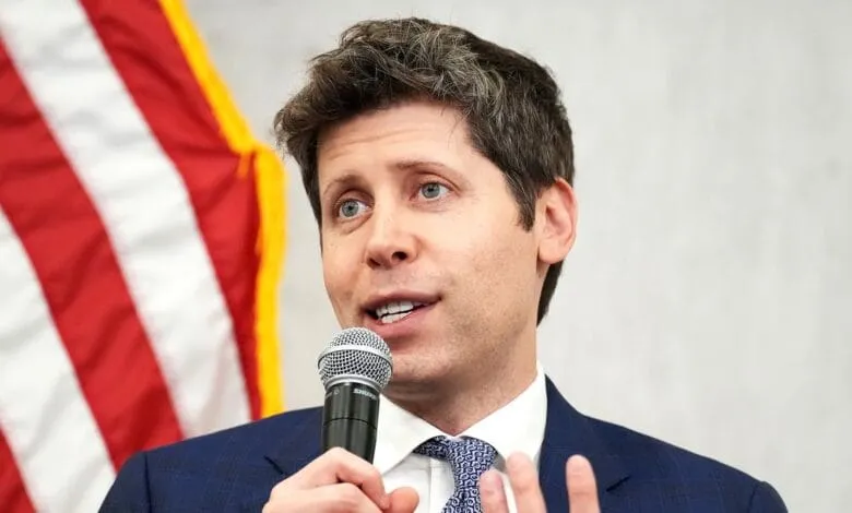 Close-up of Congressman Maxwell Frost speaking into a microphone, with an American flag blurred in the background.