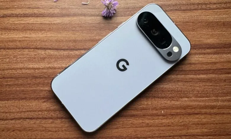 Google Pixel 10 Pro smartphone, light gray, rests on a wood surface.