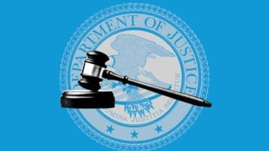 A judge's gavel rests atop the seal of the US Department of Justice, set against a bright blue background.