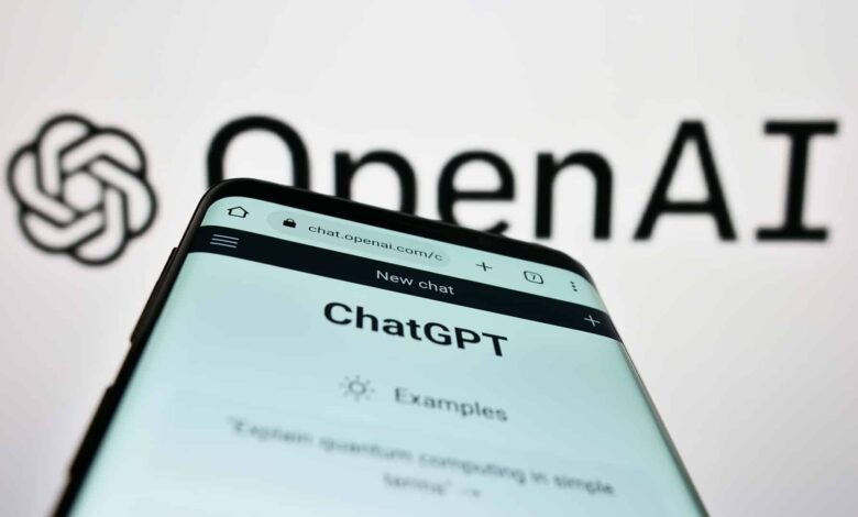 Close-up of a smartphone displaying the ChatGPT interface against a blurred OpenAI logo background.