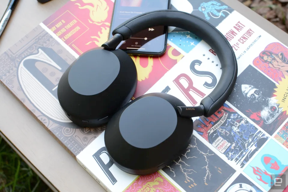 Sony WH-1000XM5 noise-canceling headphones resting on a book with colorful artwork.