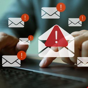 Person's hands on laptop with multiple email alert notifications.