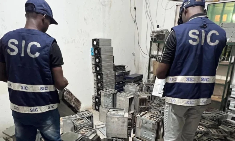 Two officers in SIC vests examine confiscated computer hardware in a raid against cybercrime.