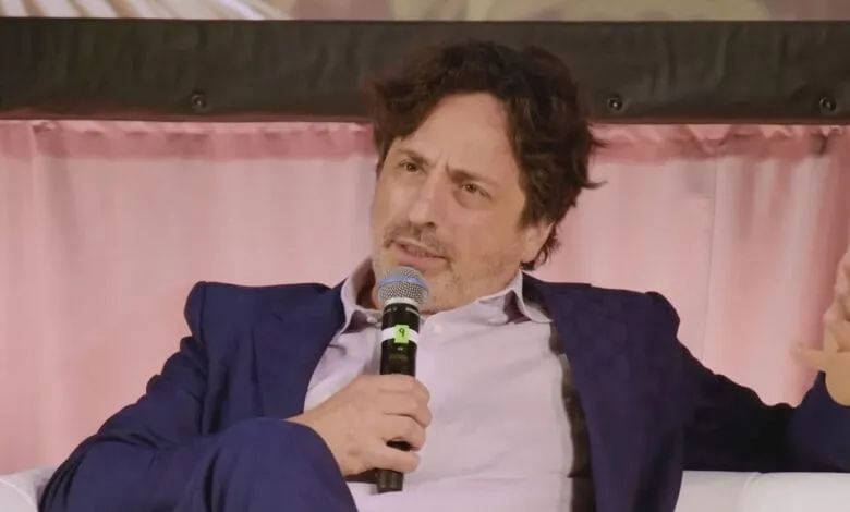 Darren Aronofsky, filmmaker, speaks at a panel discussion, holding a microphone, gesturing with his hand.