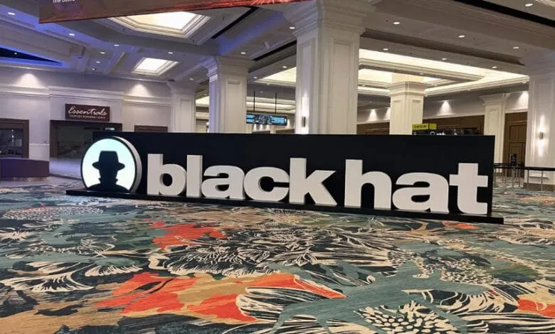 Large 'Black Hat' sign at a conference, featuring a stylized black hat logo. The setting appears to be a spacious, upscale venue.