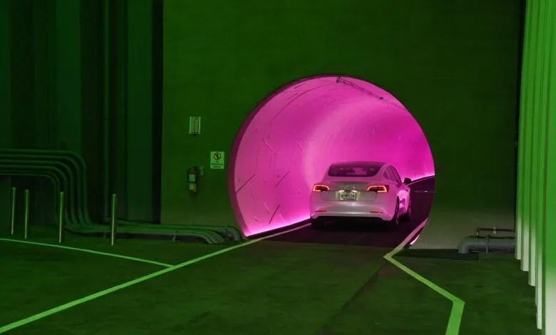 White Tesla driving into a pink-lit tunnel.