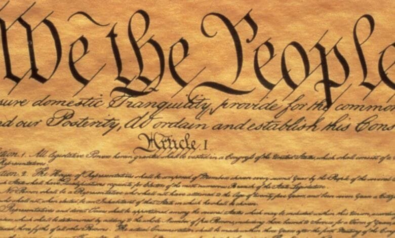 Close-up of the Preamble to the US Constitution, showing the iconic opening words, "We the People," written in elegant calligraphy on aged parchment.