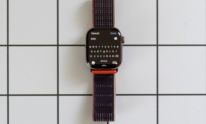 Apple Watch displaying a full keyboard on its screen, with a dark-colored woven band.