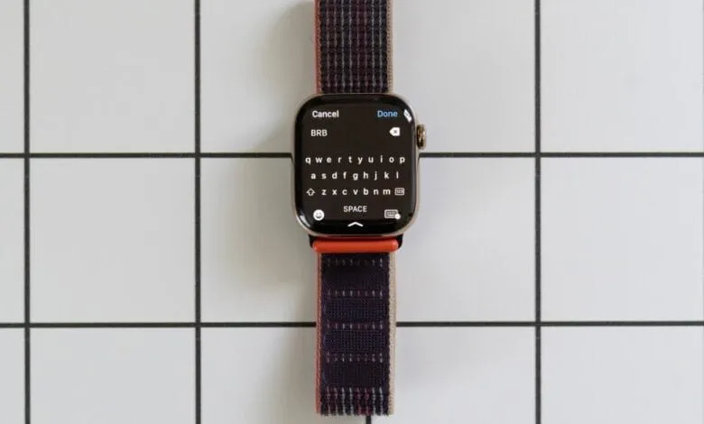 Apple Watch displaying a full keyboard on its screen, with a dark-colored woven band.