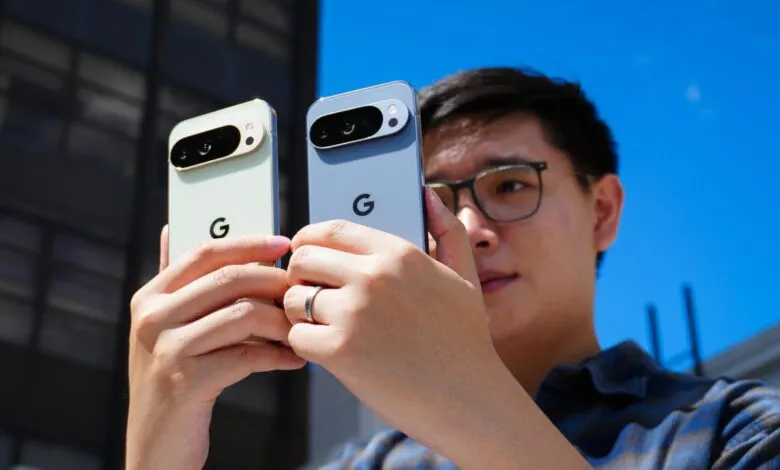 Person holding and comparing two Google Pixel phones, one light green and one gray, outdoors on a sunny day.