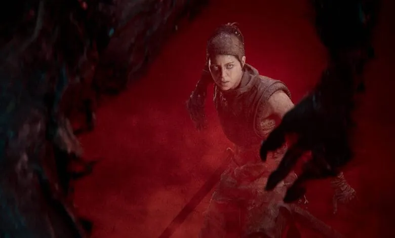 A determined woman warrior faces shadowy creatures in a bloody, red-lit scene. She holds a sword, ready for battle.