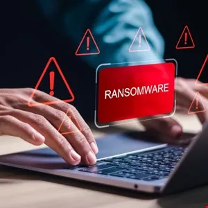 Close-up of hands on laptop with a ransomware warning, red alert triangles surround the screen.