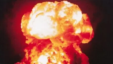 A fiery nuclear explosion mushroom cloud billows against a dark sky.