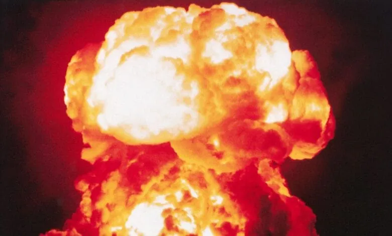 A fiery nuclear explosion mushroom cloud billows against a dark sky.