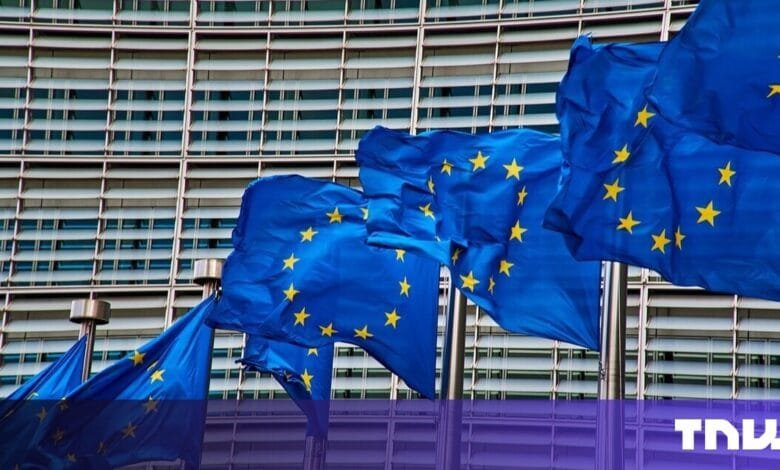 Several EU flags wave in front of a modern building. A strong symbol of European unity.