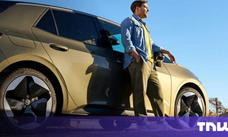 Man leans against a gold electric car, smiling at the sunny sky.