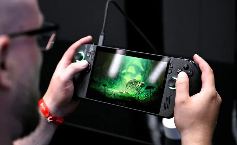 Person playing a game on a black ROG handheld gaming device with a vibrant green screen.