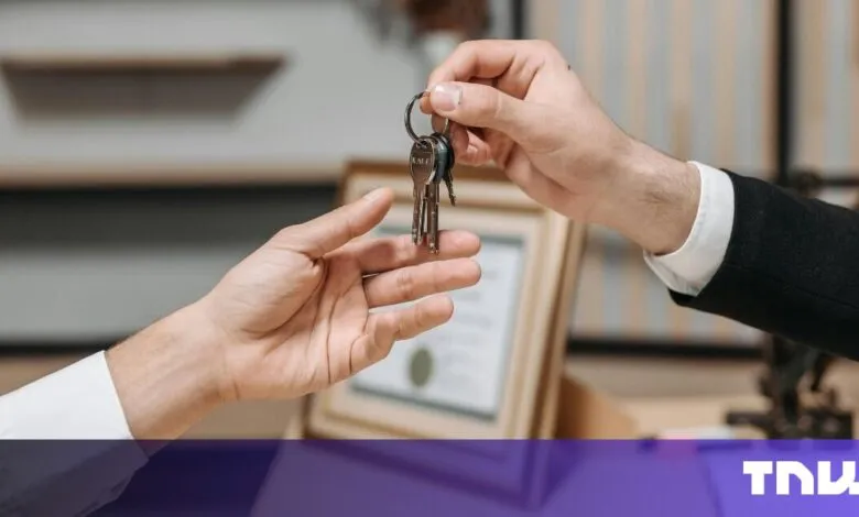 Close-up of hands exchanging house keys, symbolizing a real estate transaction or new home purchase.