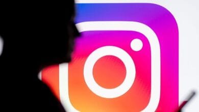 Silhouetted person looking at a large Instagram logo on a screen.