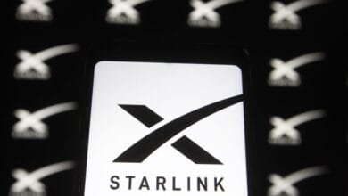 Close-up of a smartphone displaying the Starlink logo, a stylized 'X' with the word 'STARLINK' below it.