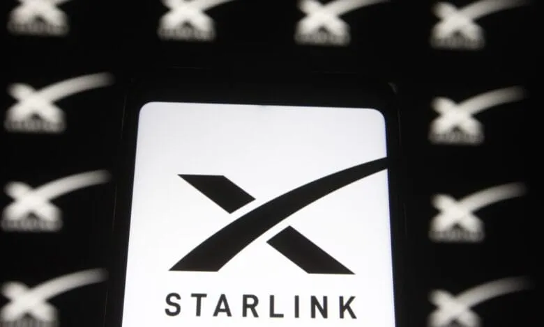Close-up of a smartphone displaying the Starlink logo, a stylized 'X' with the word 'STARLINK' below it.