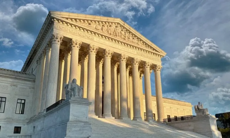 The majestic US Supreme Court building in Washington, D.C., bathed in golden sunlight against a partly cloudy sky.