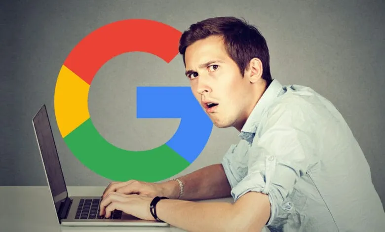 A man looks surprised while working on his laptop, with a large Google logo behind him.