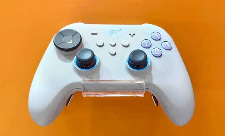 White Gulikit gaming controller with blue accents, displayed against a vibrant orange background.