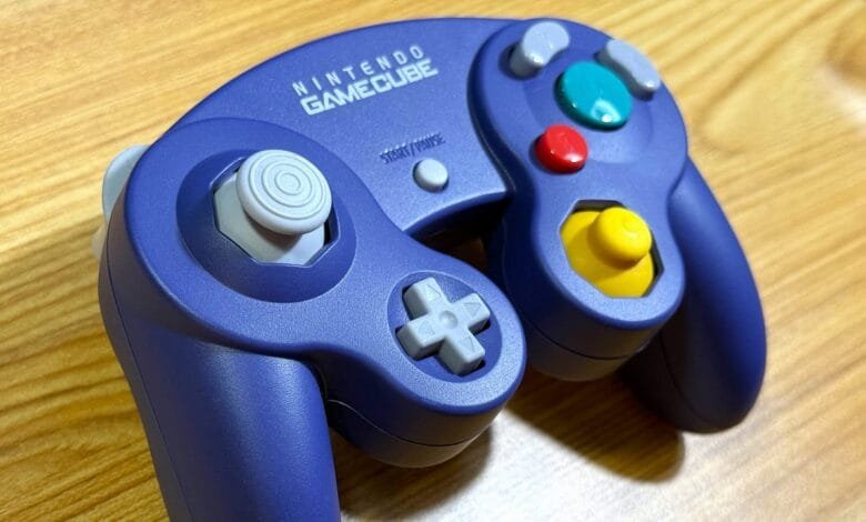 Close-up of a dark purple Nintendo GameCube controller on a wood surface.