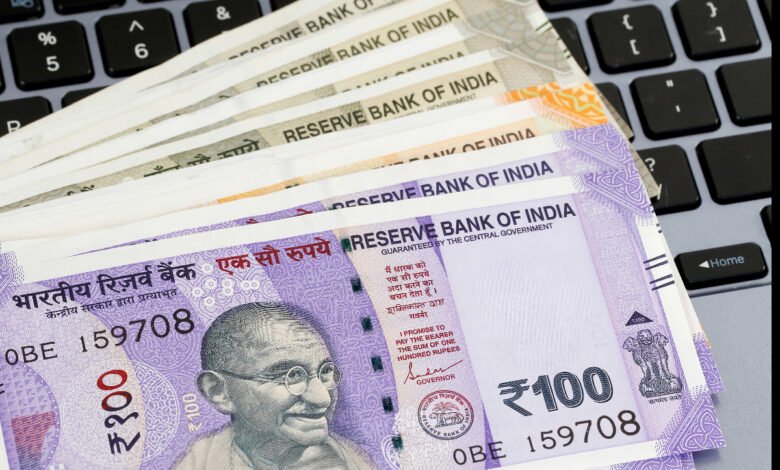Indian 100 rupee notes on a laptop keyboard, illustrating online banking or digital transactions.
