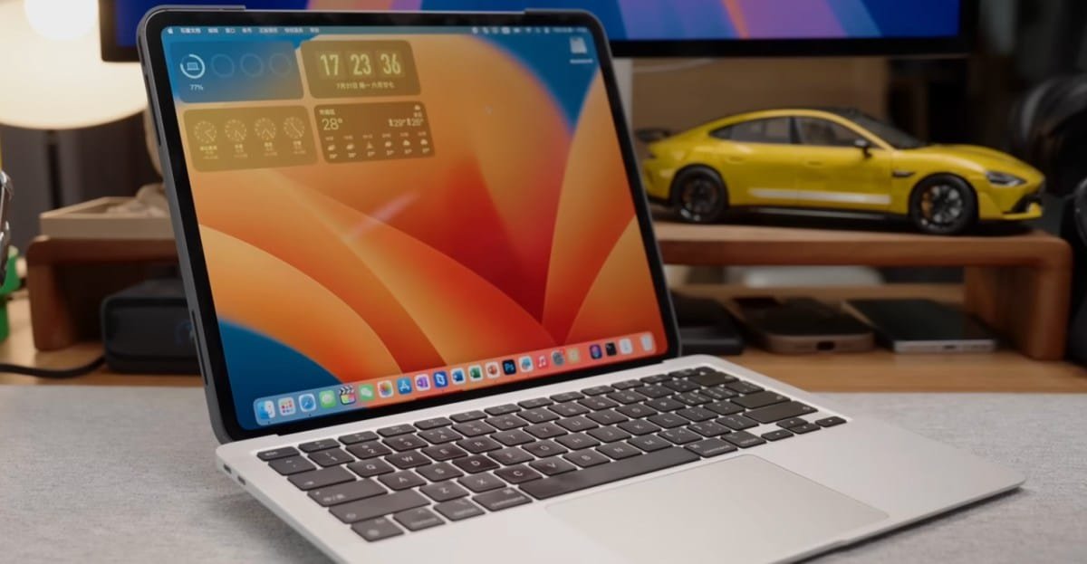 Silver iPad with keyboard attached, displaying an orange and yellow abstract wallpaper. A yellow model car sits in the background.