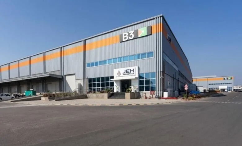 Modern gray and orange aerospace facility, JEH Aerospace, with ample parking. Building features large windows and signage.