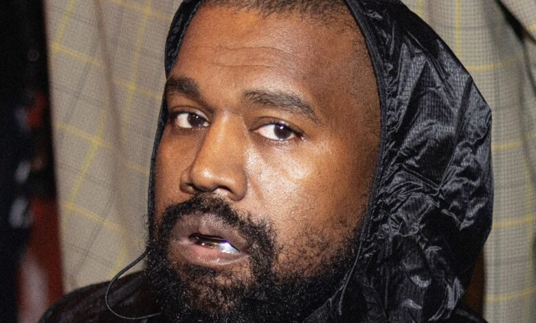 Close-up portrait of Kanye West, wearing a black hooded jacket.
