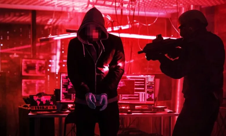 Cybercrime arrest: A handcuffed suspect in a hoodie is confronted by a law enforcement officer with a rifle in a red-lit server room.