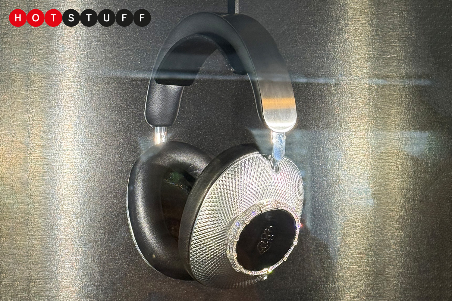 Luxury Loewe headphones encrusted with diamonds, hanging in a display case.