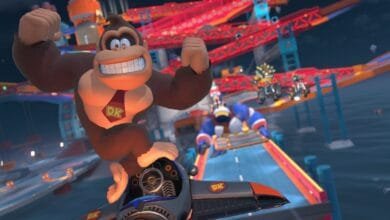 Donkey Kong, grinning, victoriously pilots a jet in a Mario Kart race, soaring above other racers on a vibrant track.