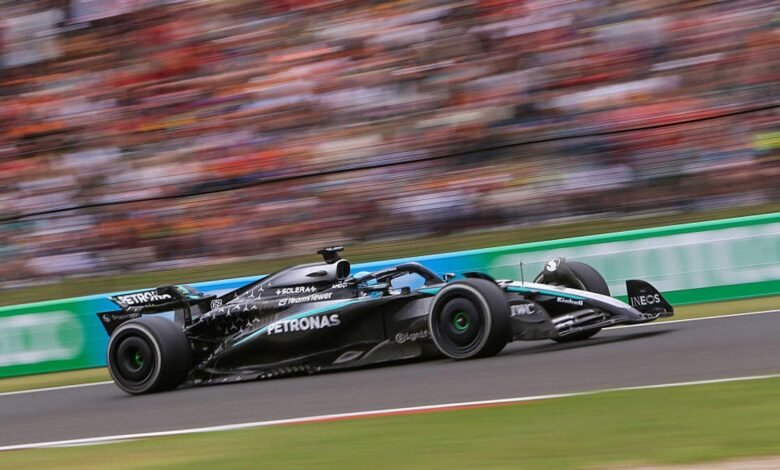 Mercedes-AMG Petronas Formula 1 car speeding around a track with blurred spectators in the background.