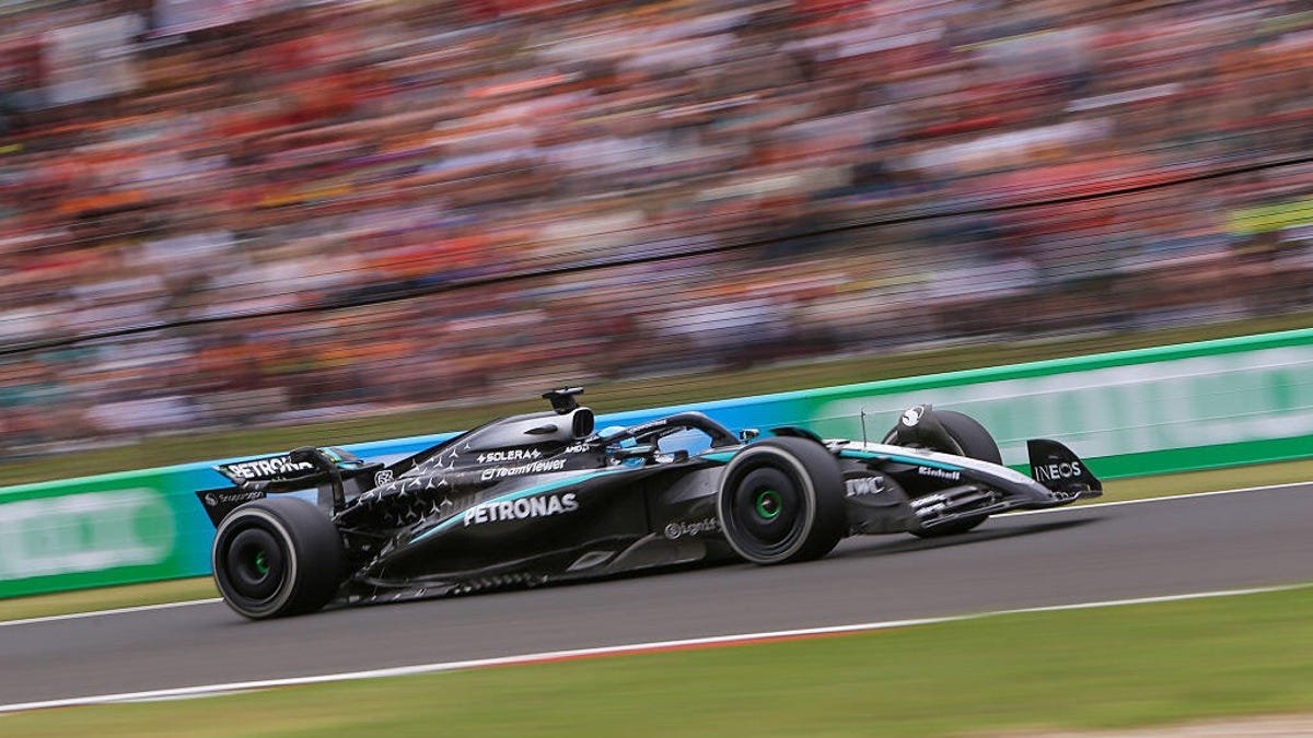 Mercedes-AMG Petronas Formula 1 car speeding around a track with blurred spectators in the background.