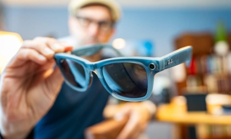 Close-up of a person holding Ray-Ban smart glasses, showcasing the blue frame and small camera.