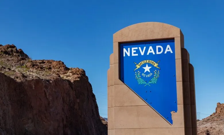 Nevada state welcome sign with blue flag and 'Battle Born' motto against desert landscape.