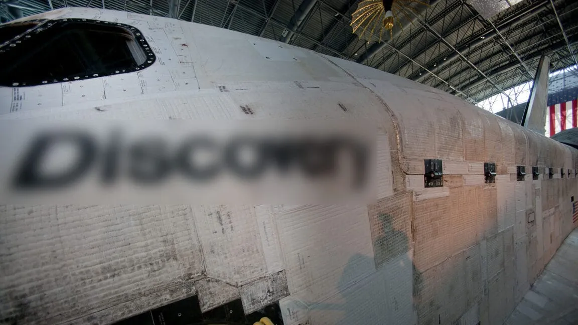 Close-up of the Space Shuttle Discovery's thermal tiles, showing their texture and the shuttle's name partially obscured.